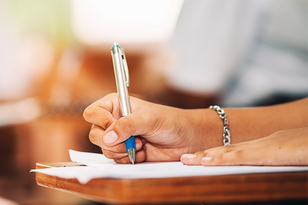hand on piece of paper writing with pen