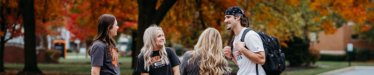 four students outside with fall trees