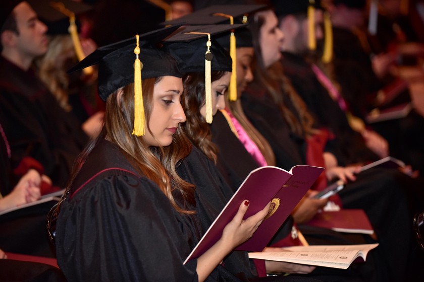 a row of seated graduates looking at the ceremony program