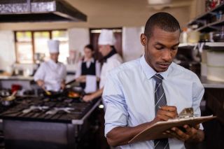 Male manager writing notes in kitchen