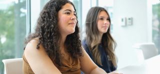 Photograph of two students sitting in class listening to their instructor