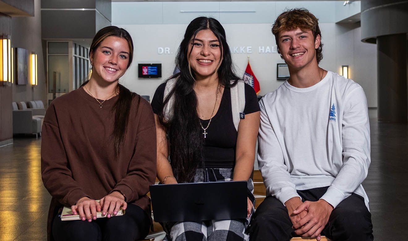 Photograph of three students smiling at the camera