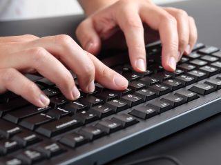 Close-up image of two hands typing on a keyboard.