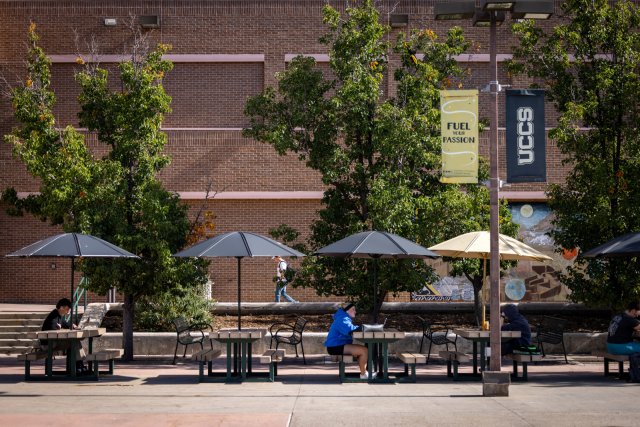 students sitting at tables on the upper plaza