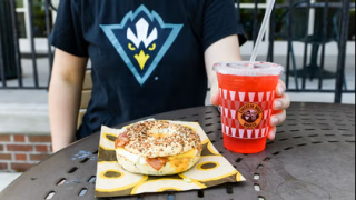 image of someone sitting in front of a bagel and drink on a table