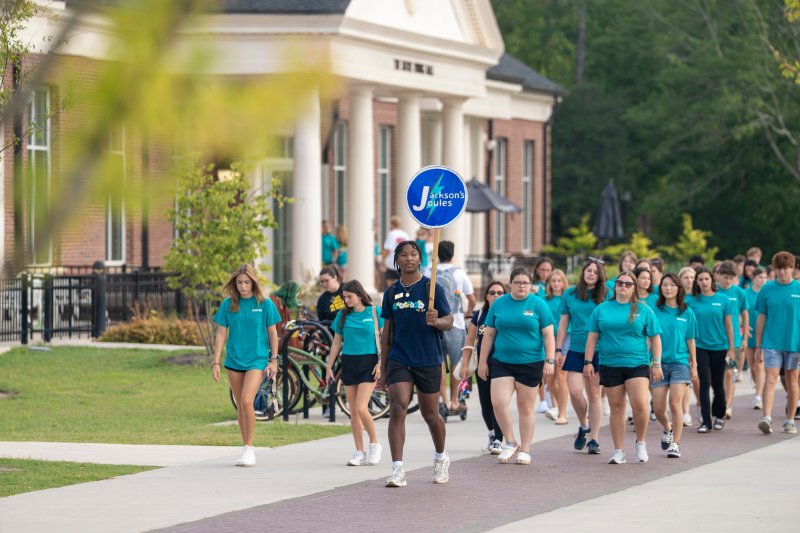 Image of an orientation leader leading a group of new students around campus