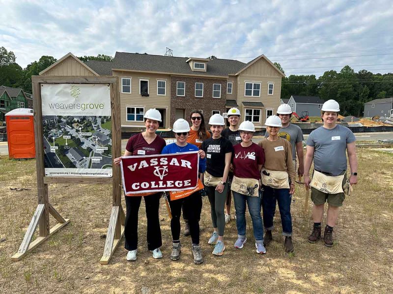  A group of volunteers for the community pose in front of a house, highlighting their commitment to helping others.