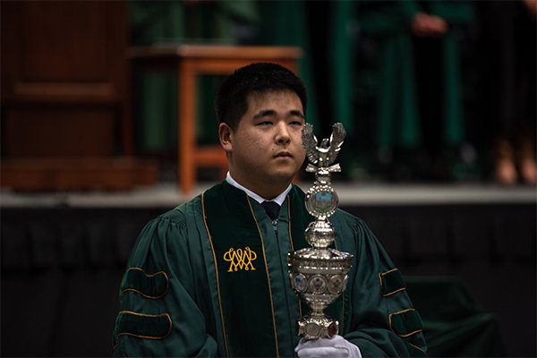Student holding the College mace on Charter Day