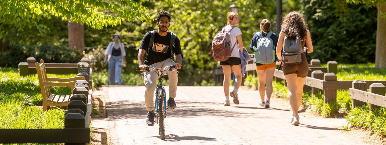 A student riding a bike while other students walk by