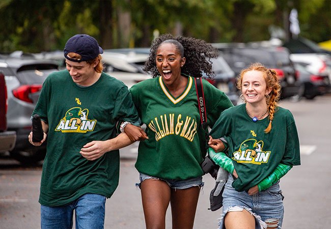 Three students walking arm in arm.
