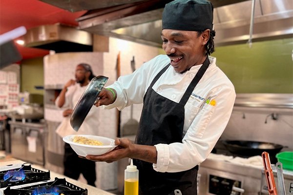 Chef plating food in a campus kitchen while cooking at a stovetop