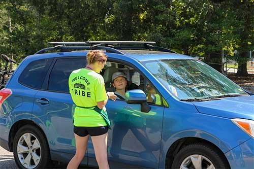 A vehicle arriving on campus greeted by students