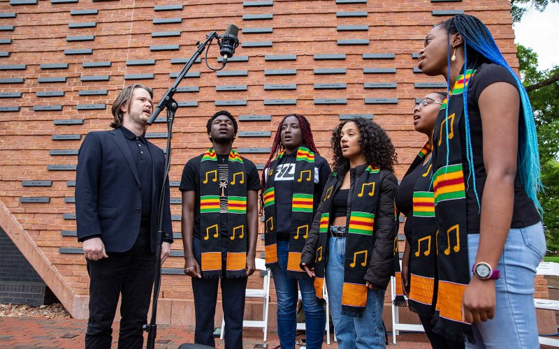 Students singing at Donning of the Kente in front of Hearth: Memorial to the Enslaved