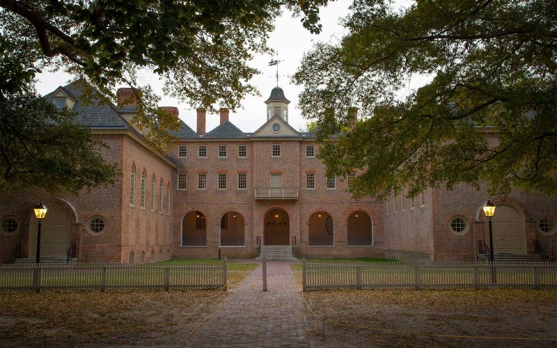 Rear view of the Wren Building with arched walkways and trees framing the scene.