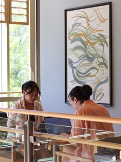 Two people on laptops seated across from one another.